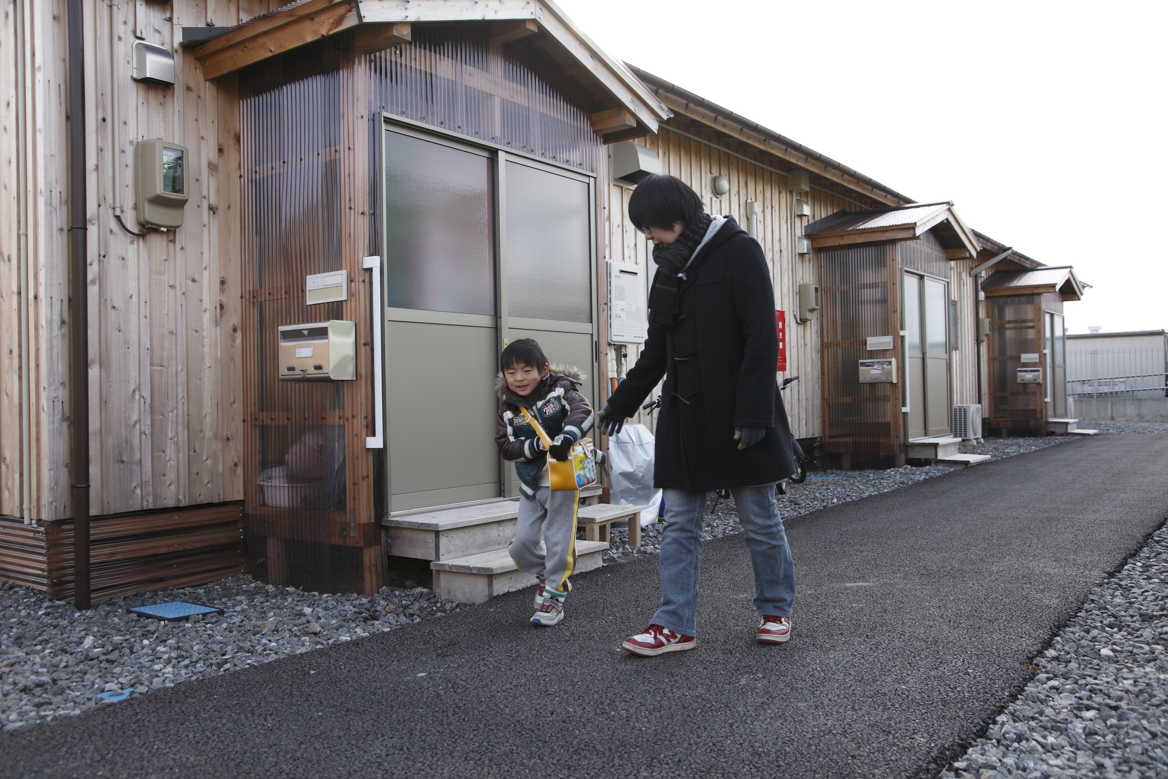 A boy and his mother outside their temporary home in the city of Iwaki. He is attending the temporary kindergarten for children from Naraha town.