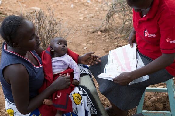 a woman and her baby meeting with a Red Cross worker