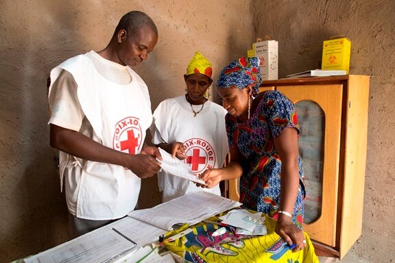 two Red Cross workers look at a paper with a woman