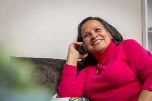 A person smiles while on the phone talking to a Friendly Calls volunteer