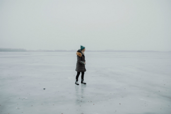 A woman wearing a parka skates on a deserted wide frozen lake