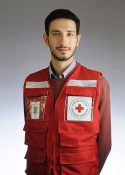 Rateb standing with arms behind his back with Canadian Red Cross red vest on