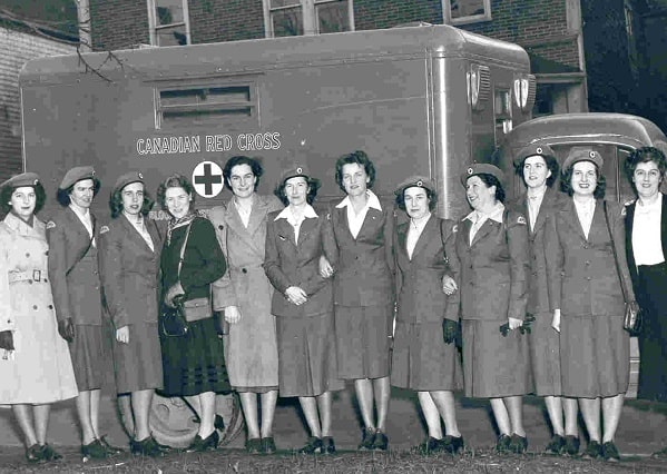 In a photo from the 1940s, a row of women standing in front of a Canadian Red Cross van