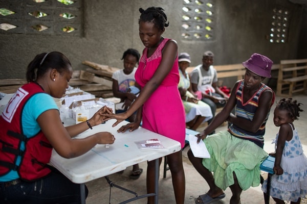 Haitian Red Cross nurse conducting a blood test for malaria on patient in Cap à Fou.