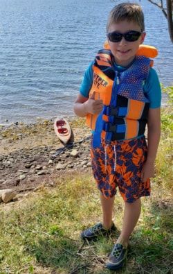 Xavier standing infront of water with lifejacket on