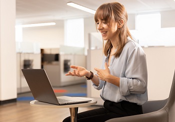 A woman sitting at a laptop smiling at the screen