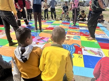 Young children looking at and standing upon a large, colourful mat