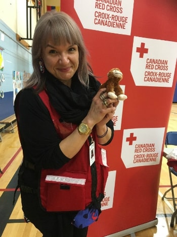 Volunteer holding teddy bear smiling.