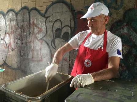 A red cross volunteer prepares food for migrants