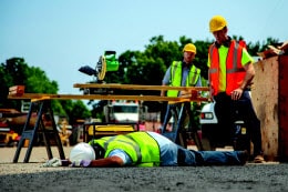 Two construction workers look and one injured colleague
