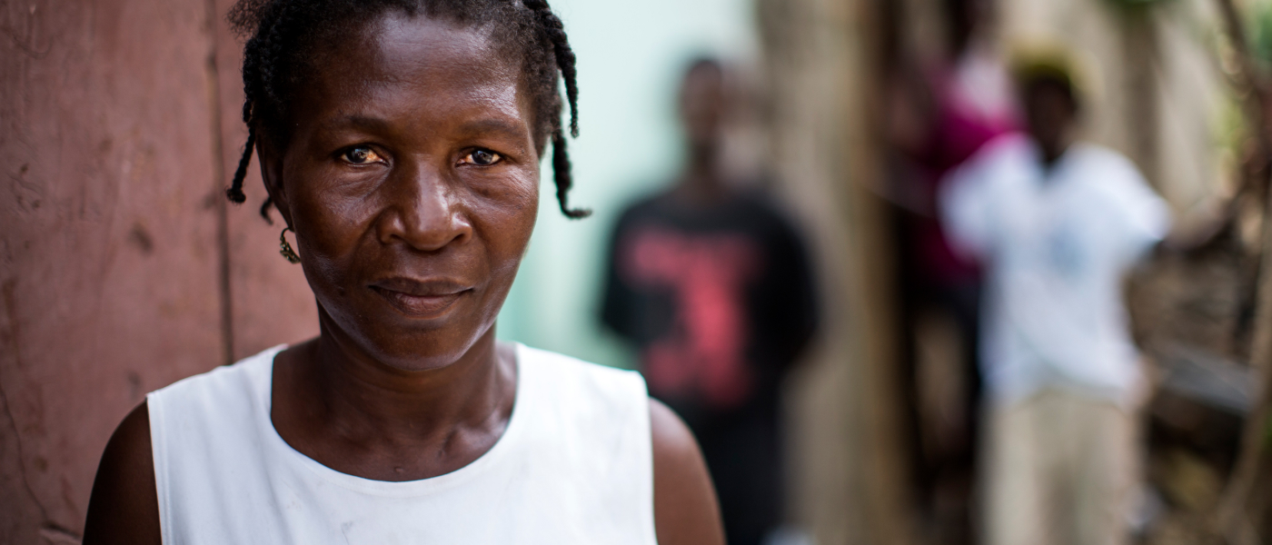 A Haitian woman in a white top looking at the camera.