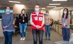Team of five Red Cross nurses stand in room, social distanced, wearing masks. 