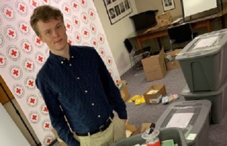 Josh, a young man, standing by boxes of supplies