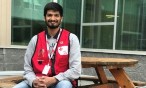 Volunteer wearing Red Cross vest, sitting on bench