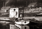A woman rowing a small  Red Cross boat