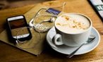 Latte and phone with headphones on table