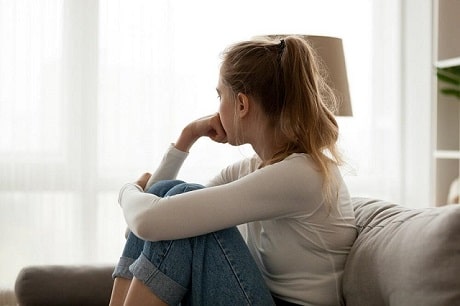 A young woman sitting alone on a couch