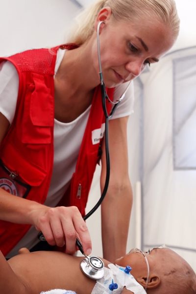 Red Cross doctor examining a baby