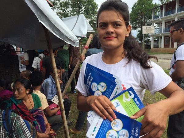 Nepal Red Cross volunteer distributes flyers on purifying water