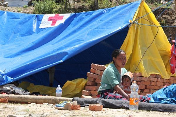 Woman and child sit outside a Red Cross tent