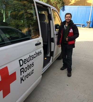 A man in Red Cross vest standing beside a Red Cross van