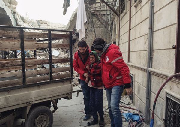 SARC volunteers help an elderly woman evacuate Aleppo