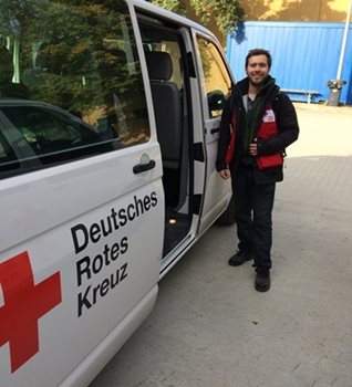 A man standing by a Red Cross van