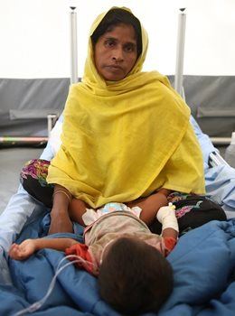 A mom watches over her baby in the isolation tent at the Red Cross Red Crescent field hospital in Bangladesh. Parents of children with measles support each other as they wait for fevers to lessen and breathing to get easier.