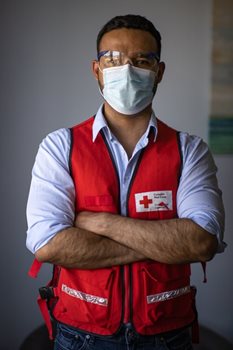 Wilson Restrepo, a psychiatrist, standing arms crossed in a Red Cross vest, and mask and goggles.