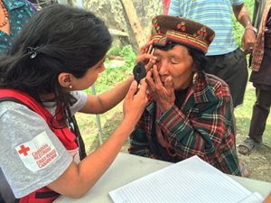 A Red Cross volunteer preforms an eye exam on an elderly woman