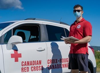 Joshua Makarov standing beside a Canadian Red Cross car