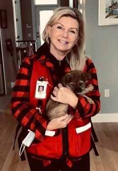 Patricia pictured in her Canadian Red Cross vest holding a small dog.