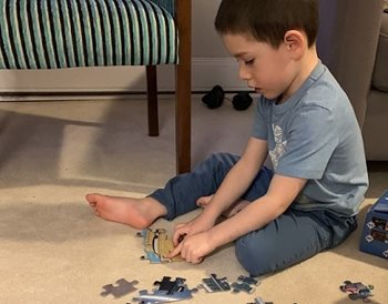 A boy sitting on the floor playing with a puzzle
