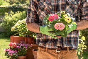 A man in gardening gloves holding flowers