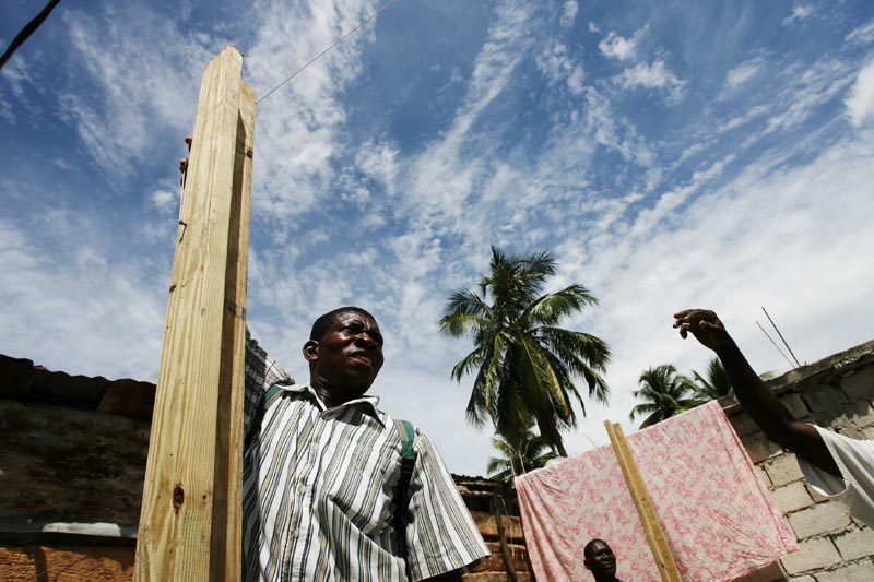 A Haitian building worker stands next to a corner post for a new Red Cross transitional shelter in Petit-Goâve. 