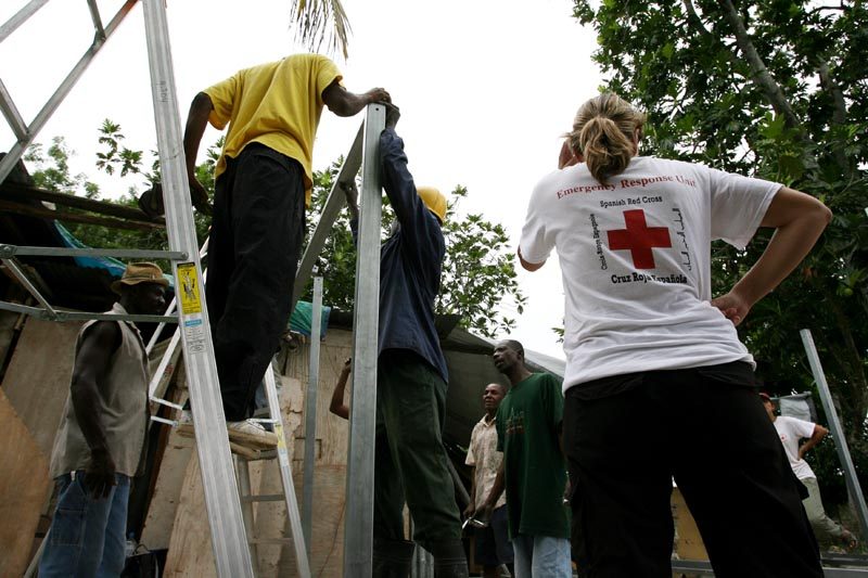 Spanish Red Cross construction delegates near Leogane assist Haitian builders working on the first Red Cross transitional shelters to be allocated to quake-affected families.