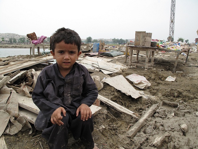 A small boy sits amongst the debris left behind in the wake of the floods in Nowshera town.