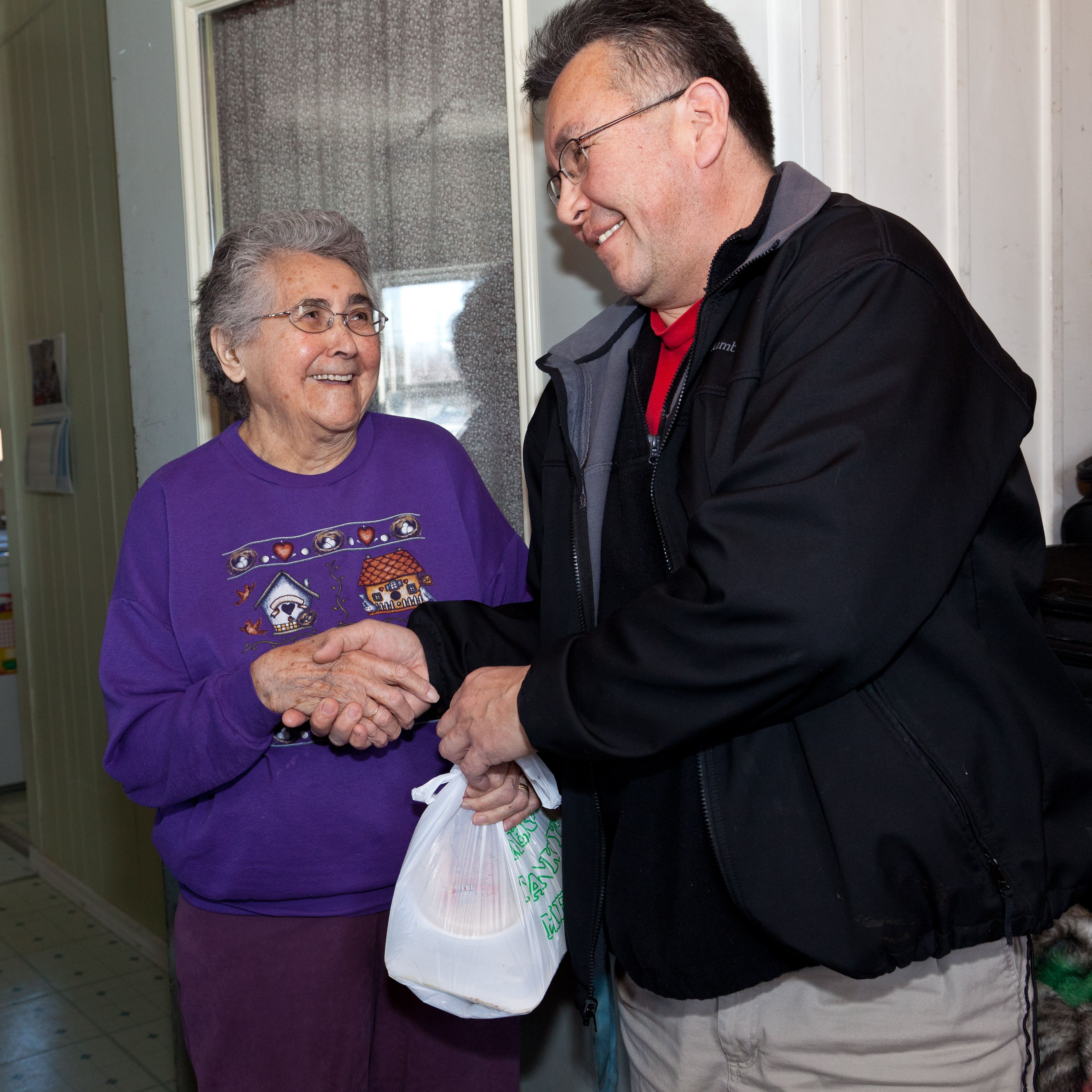 Moosonee Mayor Victor Mitchell delivers a meal to Maude Tyrer. Photo credit: Paul Lantz