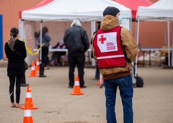 Ian in a mask and Canadian Red Cross vest looking around tents set up for registration in Alberta flooding