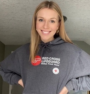 A smiling young woman in a Red Cross lifeguard sweater