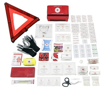 A roadside Red Cross first aid kit open with contents laid out