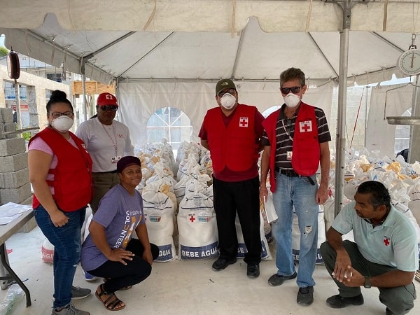 Red Cross workers from Belize standing under a tent with masks on.