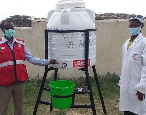 Somaliland Red Crescent workers standing beside a water station.
