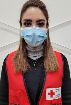 A woman in a mask and Canadian Red Cross vest