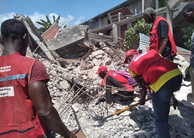 A Red Cross team looking through a collapsed building