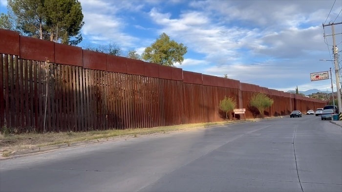 A large red fence running along a border