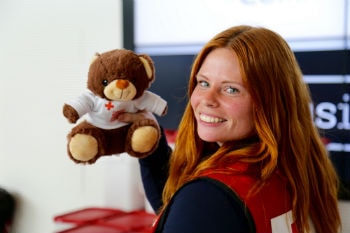 Volunteer smiling while holding a teddy bear.