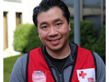 A man in a Red Cross vest smiling at the camera