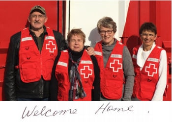 Three female and one male Red Cross volunteer with 'Welcome Home' written underneath