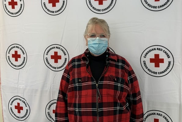 Barb in glasses and mask standing in front of the Canadian Red Cross logo